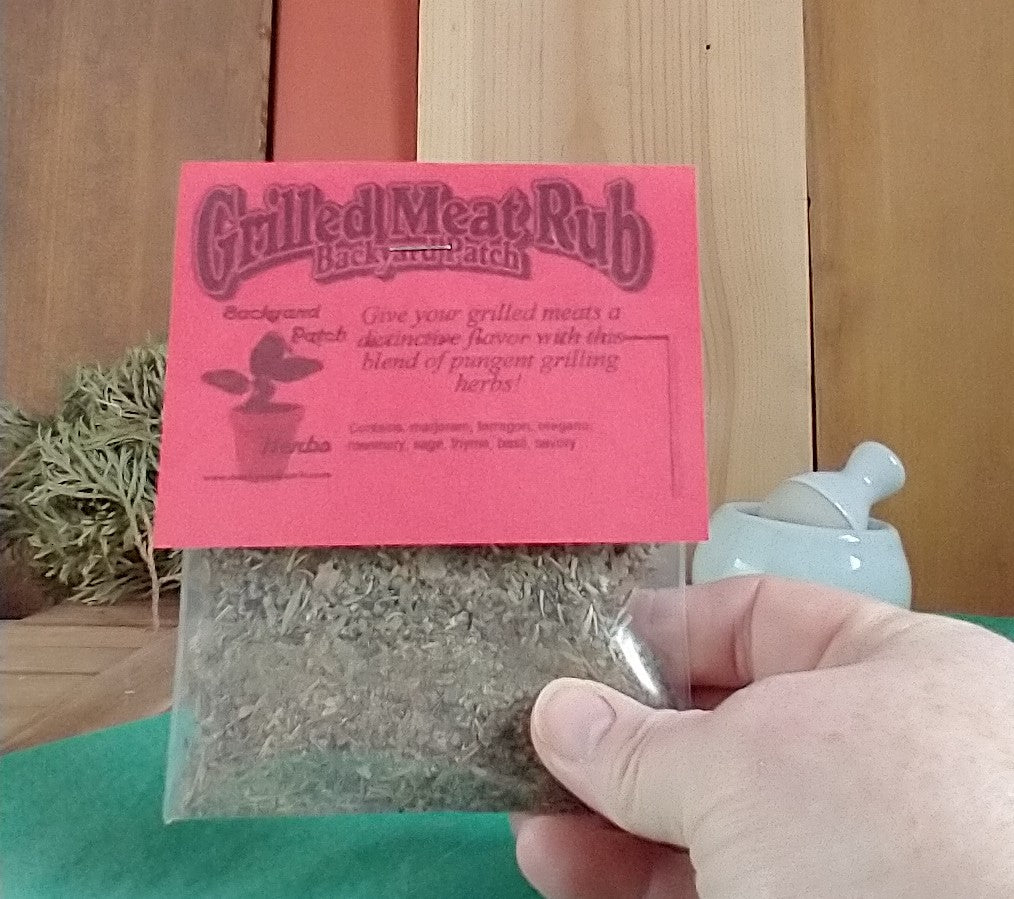 Grilled Meat Rub package with red label held by a hand against a wooden background with mortar