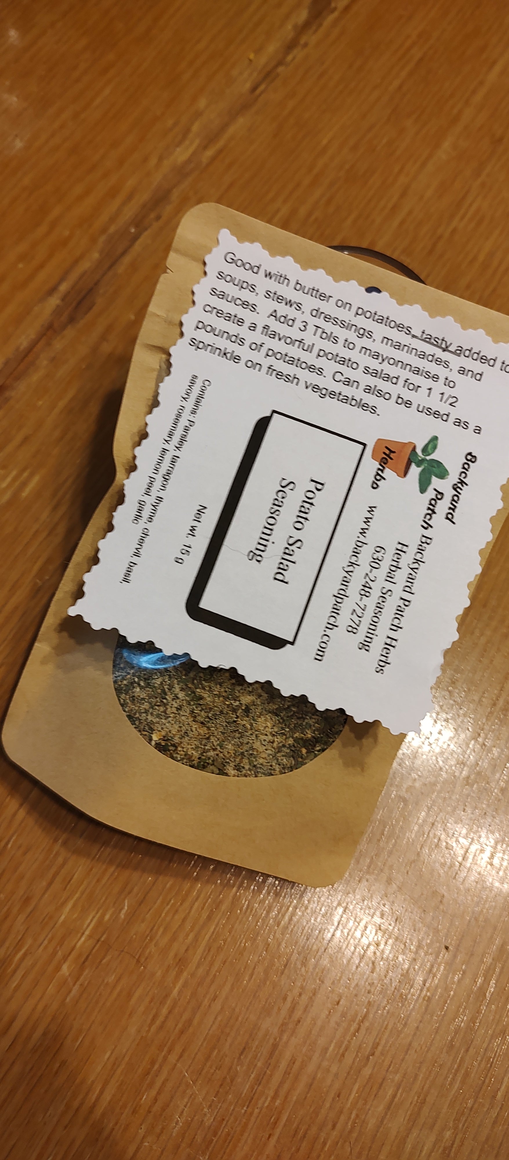 Eco kraft bag of Herbal seasoning labeled Potato Salad Seasoning on a wooden surface