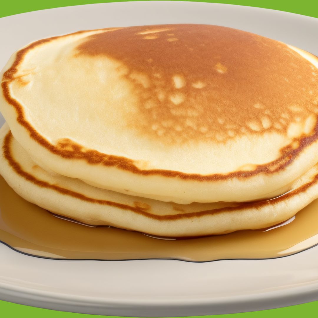 stack of two pancakes on a puddle of syrup on a white plate