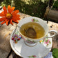 floral tea cup with brewed gold colored rest easy tea and a tea ball